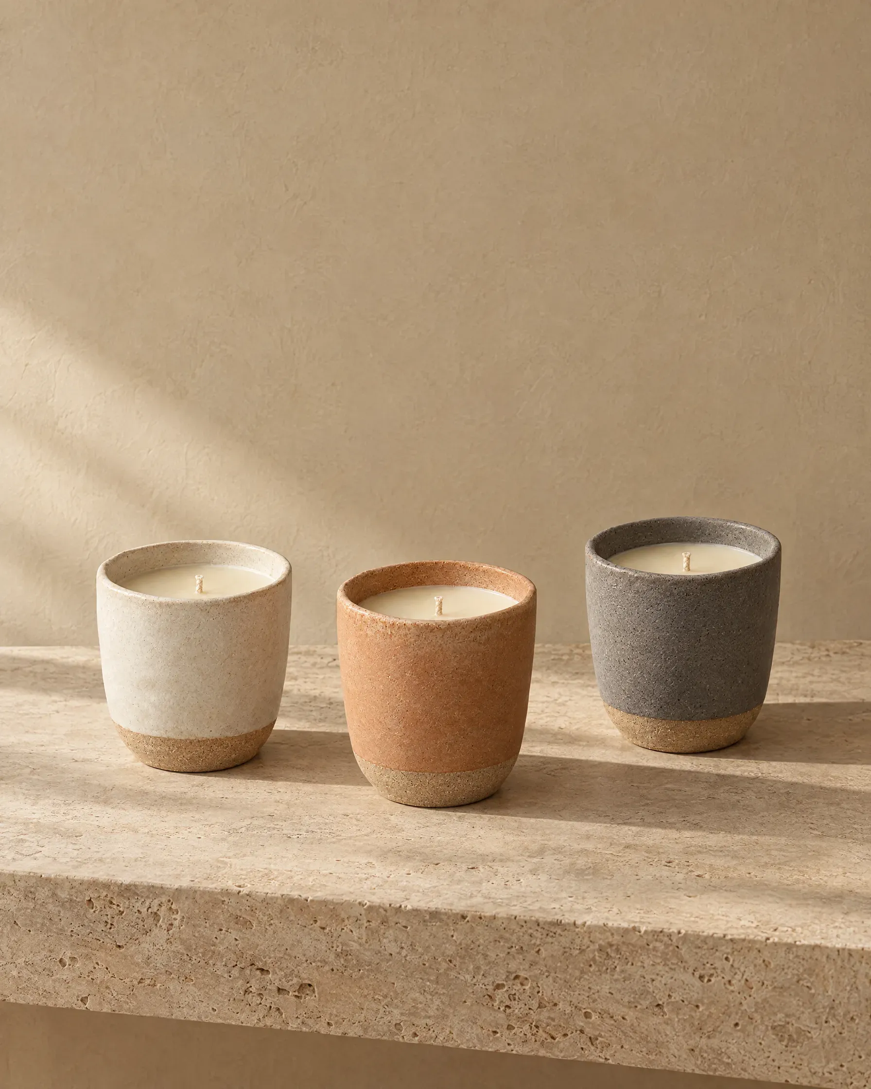 Three beeswax candles in stoneware vessels glazed in bone, clay and ash