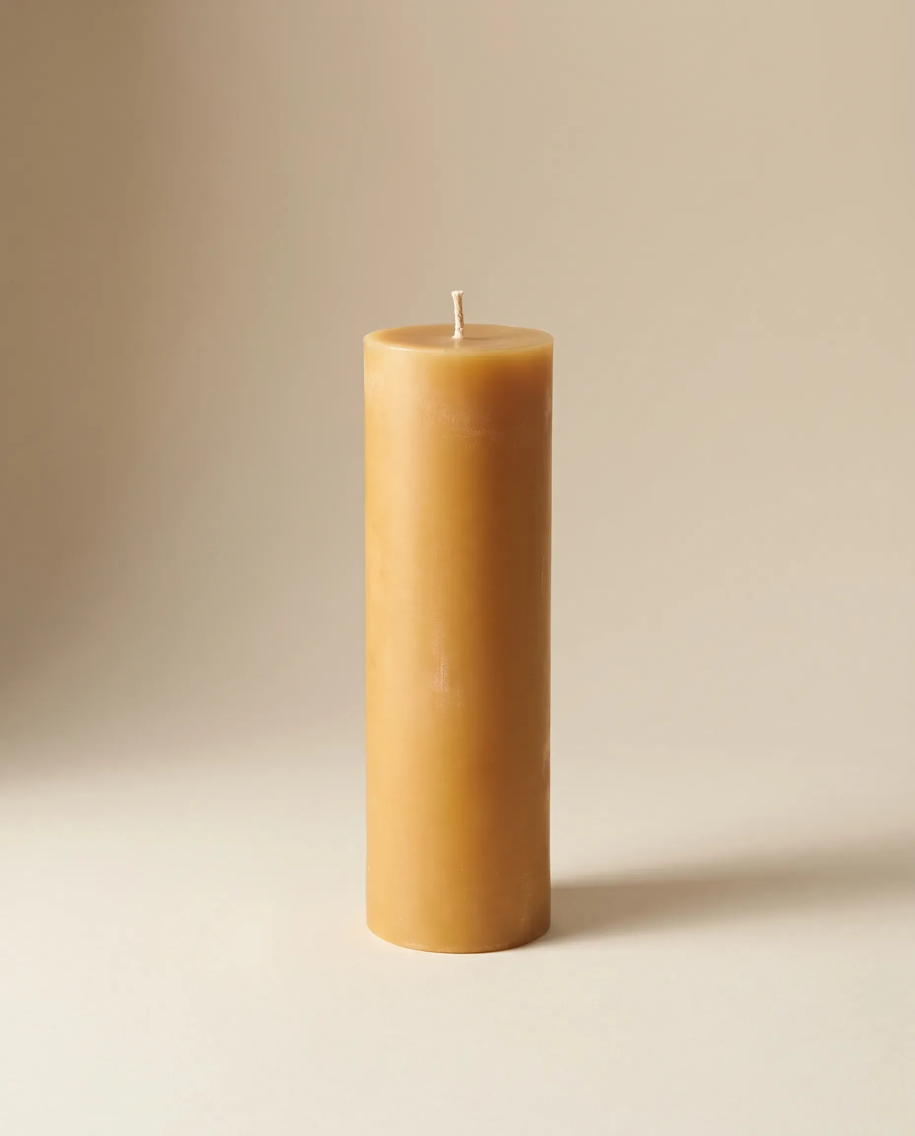 A tall golden beeswax pillar candle, 20 cm