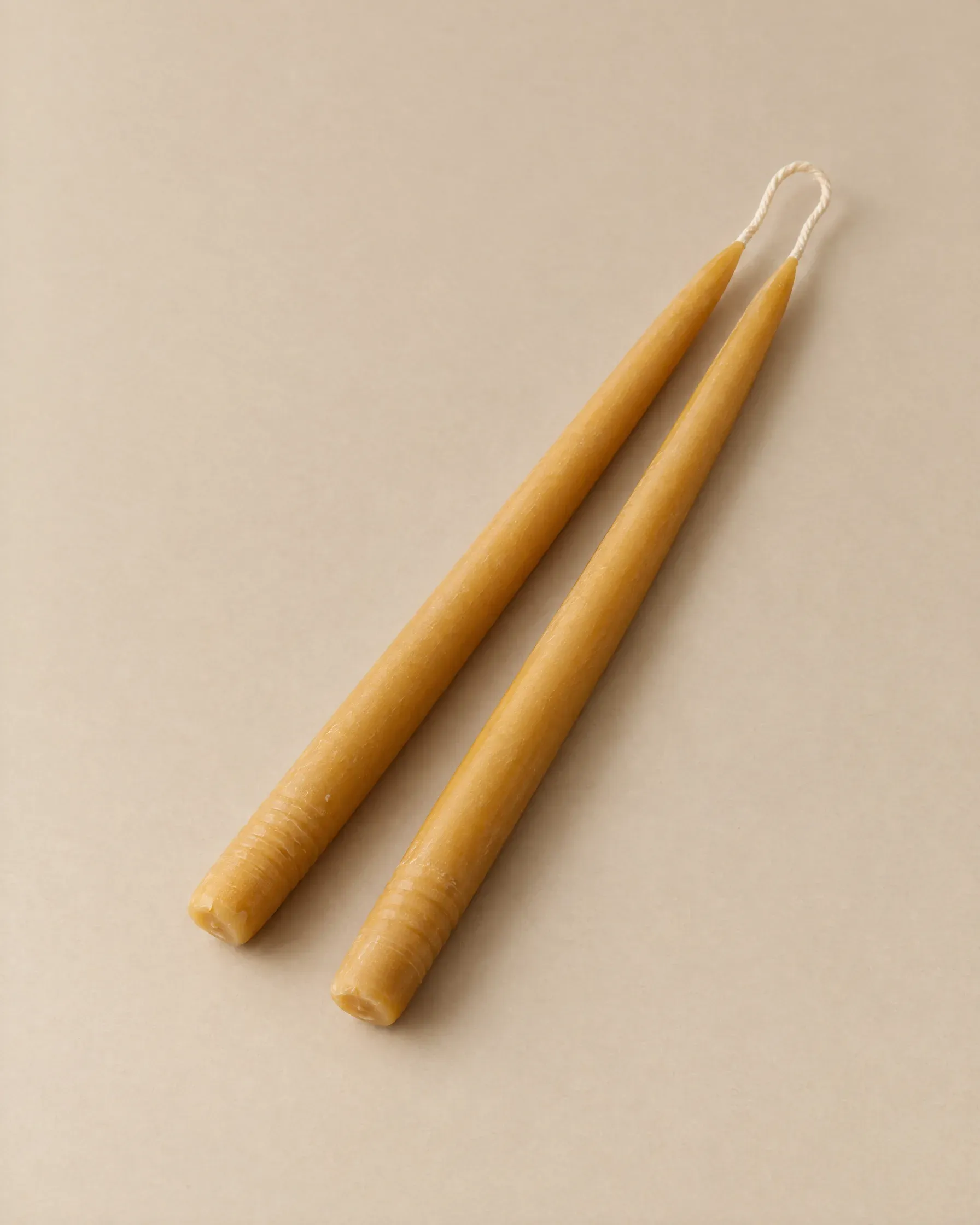 A pair of hand-dipped golden beeswax taper candles joined at the wick
