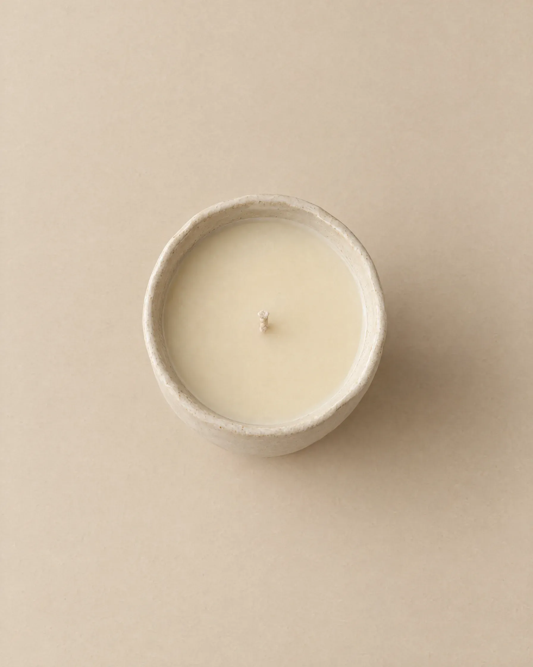 The Bone vessel from above: a beeswax candle in a bone-white stoneware cup